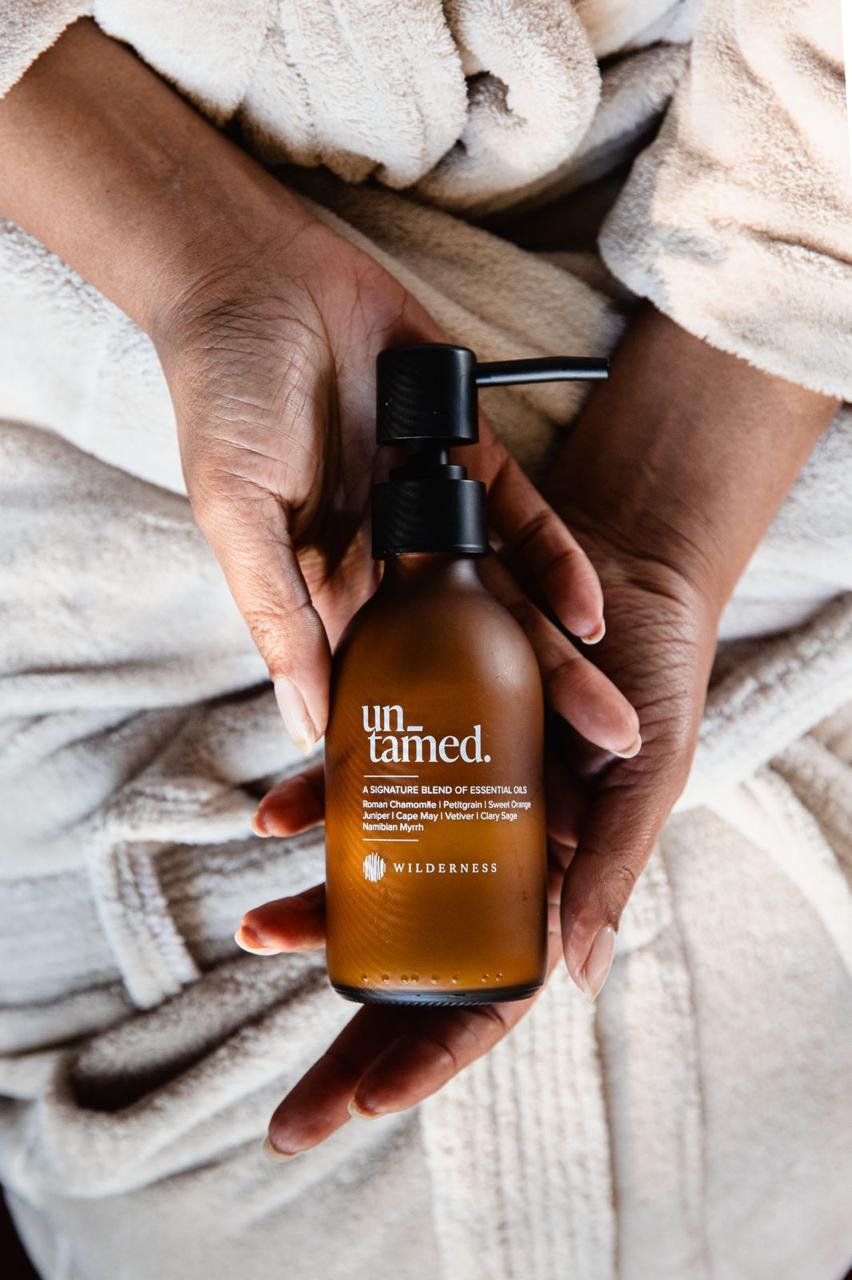 Person holding a 'untamed' bottle with a neutral background